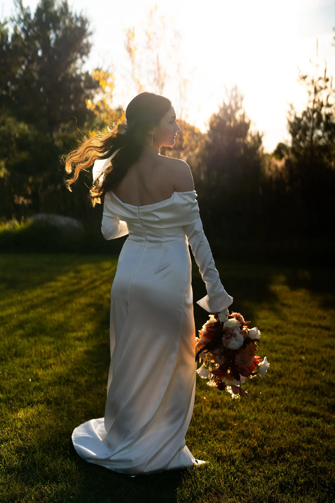 A woman in white dress holding flowers and walking